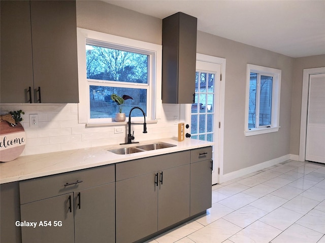 kitchen featuring gray cabinets, sink, and tasteful backsplash