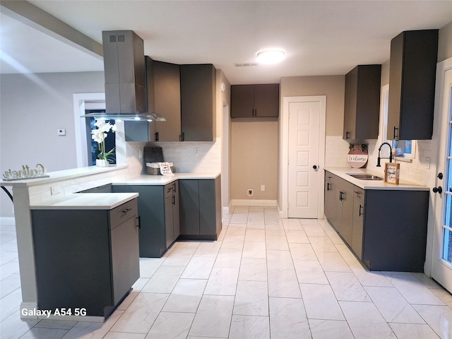 kitchen with island exhaust hood, decorative backsplash, sink, and gray cabinetry