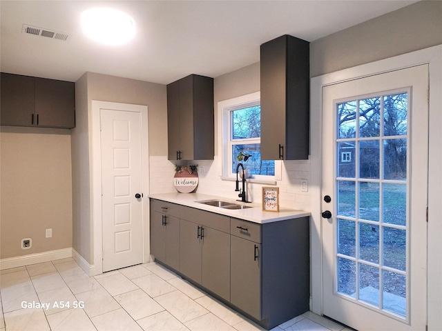 kitchen featuring tasteful backsplash, gray cabinetry, sink, and light tile patterned floors