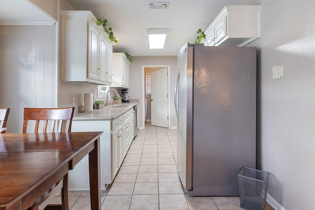 kitchen with stainless steel refrigerator, white cabinetry, light tile patterned flooring, and light stone countertops