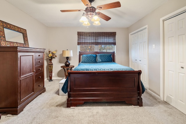 carpeted bedroom featuring ceiling fan and multiple closets