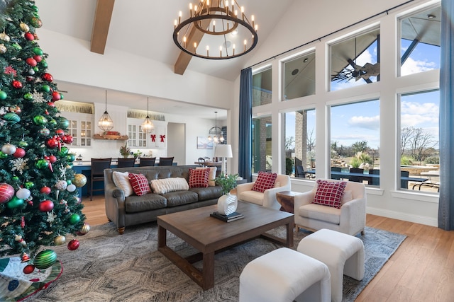 living room with hardwood / wood-style flooring, beam ceiling, a towering ceiling, and an inviting chandelier