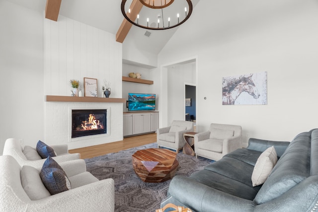 living room with high vaulted ceiling, built in features, a large fireplace, wood-type flooring, and a chandelier