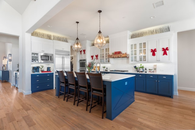 kitchen featuring pendant lighting, built in appliances, white cabinetry, and blue cabinets