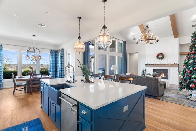 kitchen featuring blue cabinetry, a kitchen island with sink, dishwasher, and pendant lighting