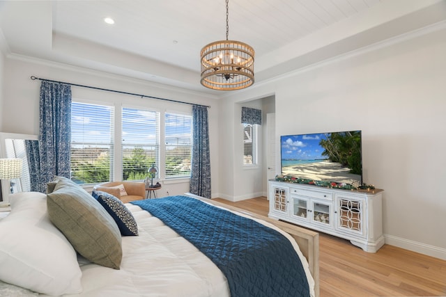 bedroom featuring a raised ceiling, light wood-type flooring, and an inviting chandelier