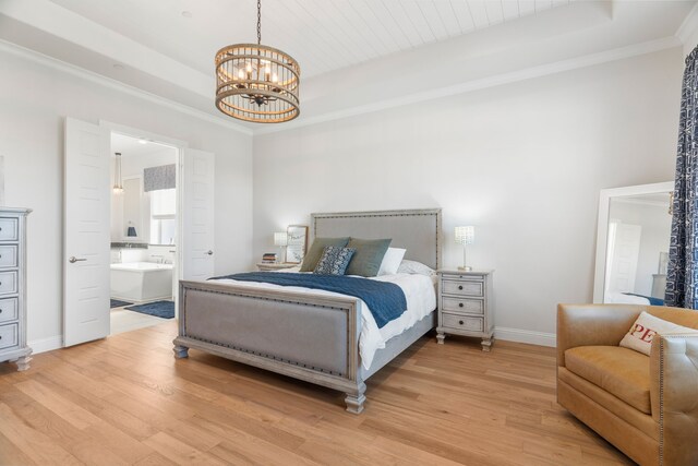 bedroom featuring a raised ceiling, ensuite bath, a chandelier, and hardwood / wood-style flooring