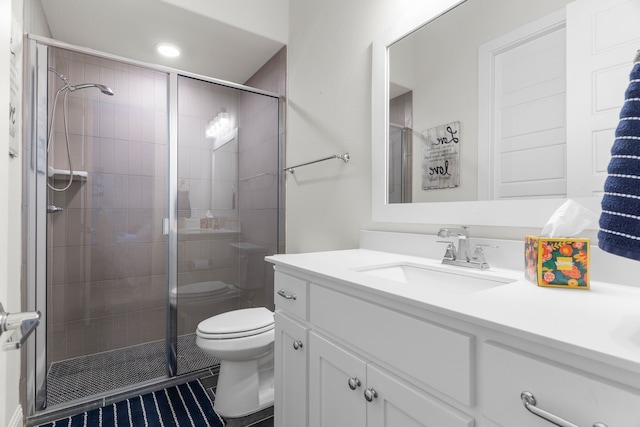 bathroom featuring tile patterned floors, vanity, toilet, and a shower with shower door