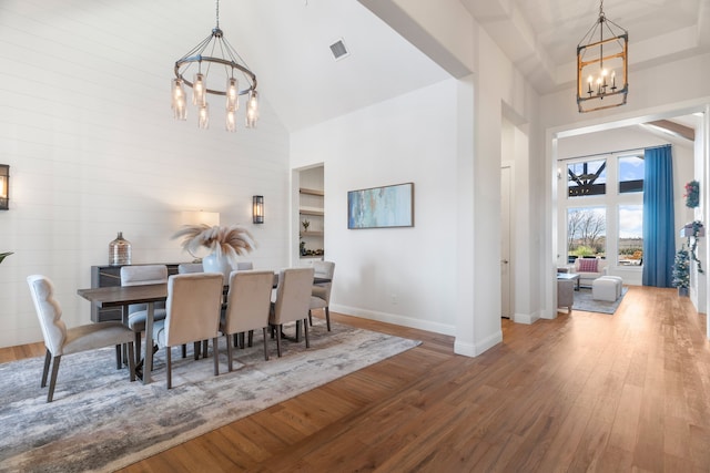 dining space with hardwood / wood-style floors, a chandelier, and a high ceiling