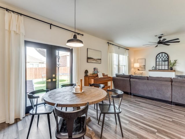 dining area with french doors, ceiling fan, and light wood-type flooring