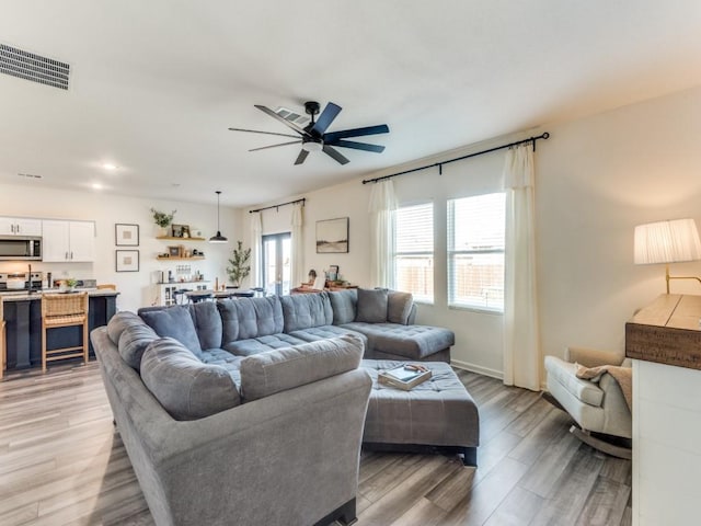 living room with ceiling fan and light hardwood / wood-style flooring