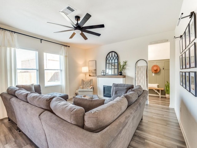 living room featuring ceiling fan, a barn door, and light wood-type flooring