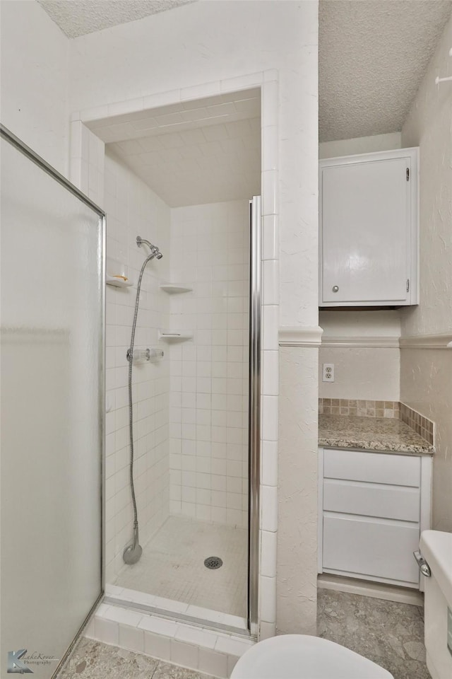 bathroom with a textured ceiling, a shower with shower door, and toilet