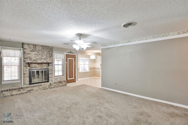 unfurnished living room featuring a textured ceiling, light colored carpet, a brick fireplace, and ceiling fan