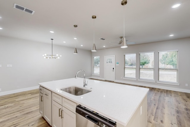 kitchen featuring sink, pendant lighting, dishwasher, white cabinetry, and an island with sink