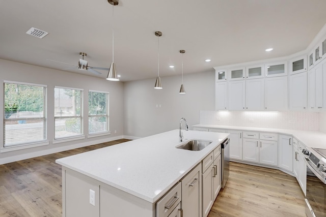 kitchen with a center island with sink, sink, decorative light fixtures, white cabinetry, and stainless steel appliances