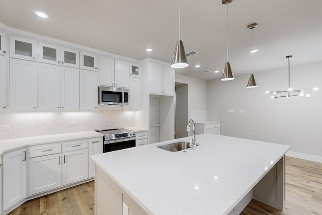 kitchen with pendant lighting, white cabinetry, a kitchen island with sink, and appliances with stainless steel finishes