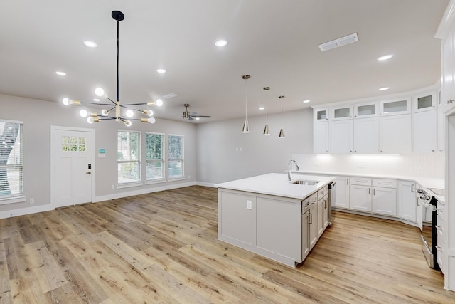 kitchen featuring sink, stainless steel appliances, pendant lighting, a kitchen island with sink, and white cabinets