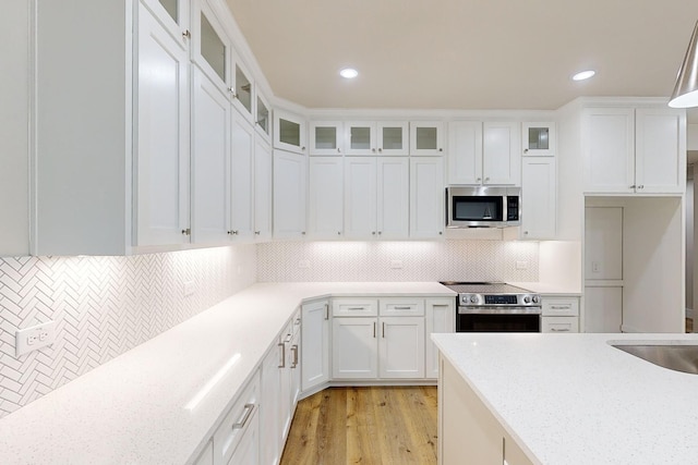 kitchen with white cabinets, decorative backsplash, stainless steel appliances, and light stone countertops