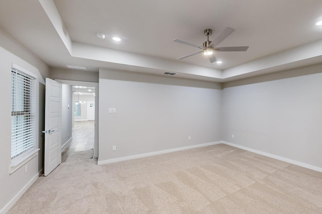 interior space featuring a raised ceiling, ceiling fan, and light carpet