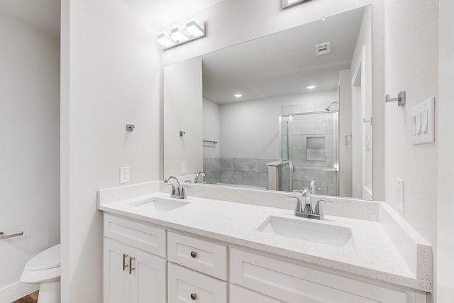 bathroom with vanity, a shower with shower door, and toilet