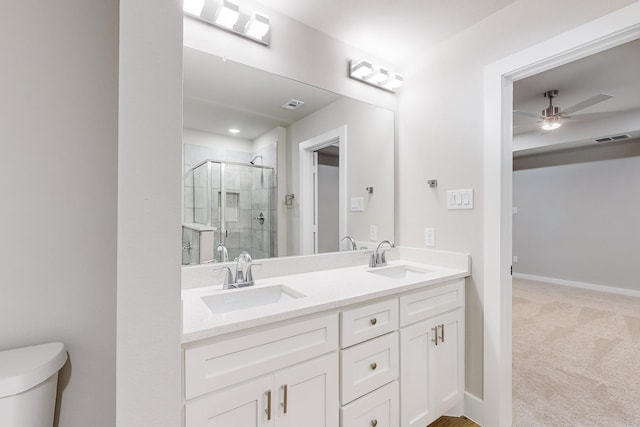 bathroom featuring vanity, a shower with door, toilet, and ceiling fan