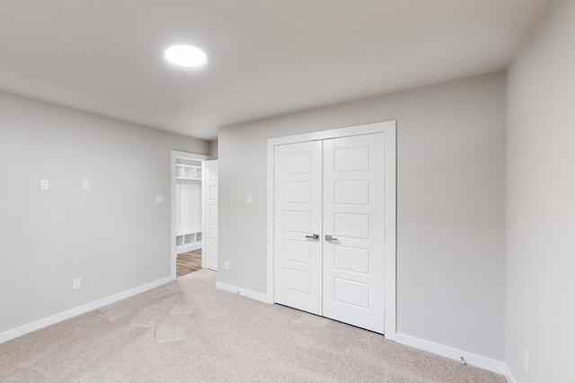 unfurnished bedroom with light carpet and a closet