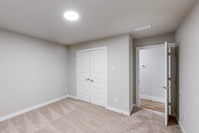 unfurnished bedroom with light colored carpet and a closet