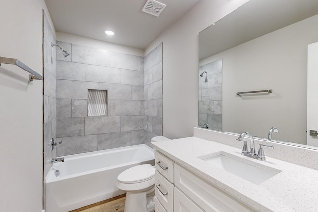 full bathroom with hardwood / wood-style floors, vanity, toilet, and tiled shower / bath