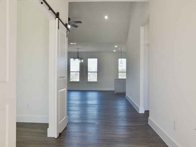 hall with a barn door, dark hardwood / wood-style flooring, and a chandelier