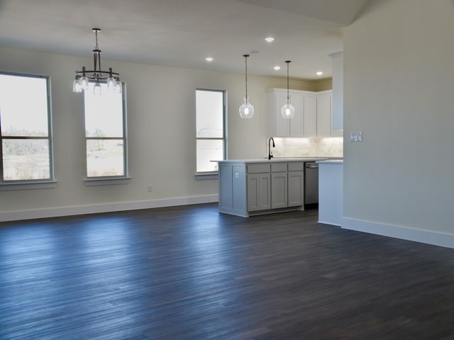 kitchen with dishwasher, sink, an island with sink, pendant lighting, and white cabinets