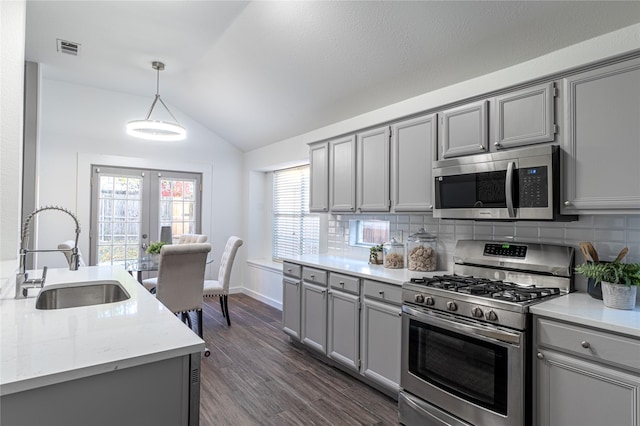 kitchen with sink, hanging light fixtures, stainless steel appliances, tasteful backsplash, and lofted ceiling