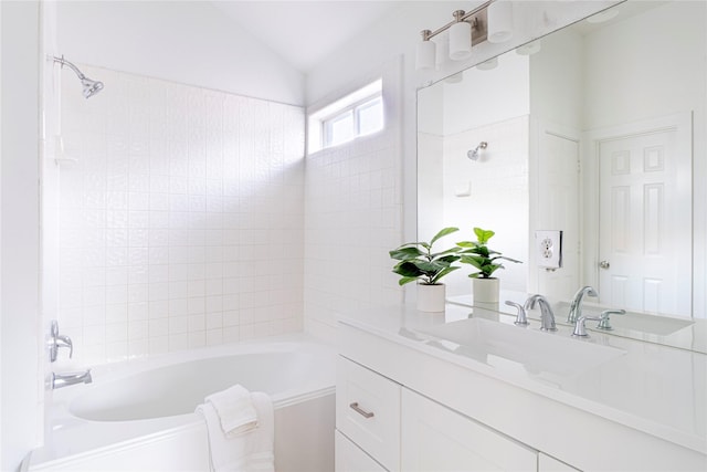 bathroom with tiled shower / bath combo, lofted ceiling, and vanity