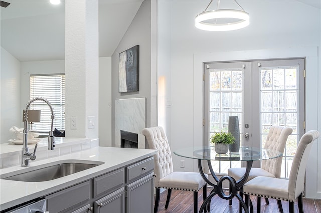 dining room with lofted ceiling, french doors, sink, a fireplace, and dark hardwood / wood-style flooring