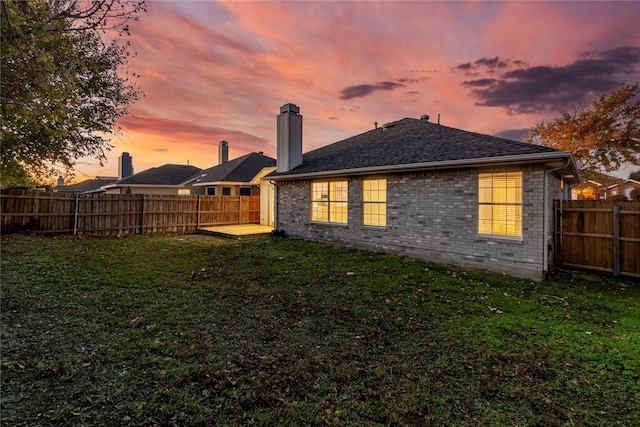 back house at dusk featuring a yard