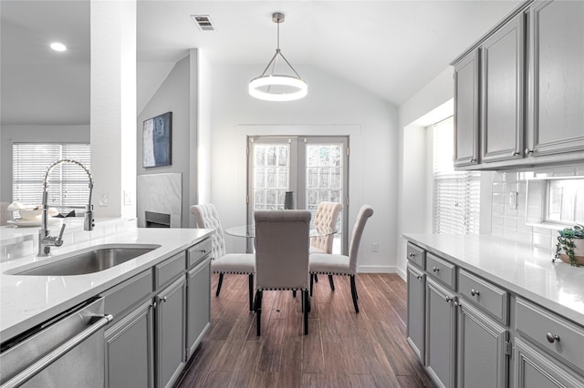 kitchen featuring dishwasher, sink, hanging light fixtures, vaulted ceiling, and gray cabinets