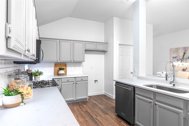 kitchen featuring stainless steel dishwasher, sink, gray cabinets, dark hardwood / wood-style floors, and lofted ceiling