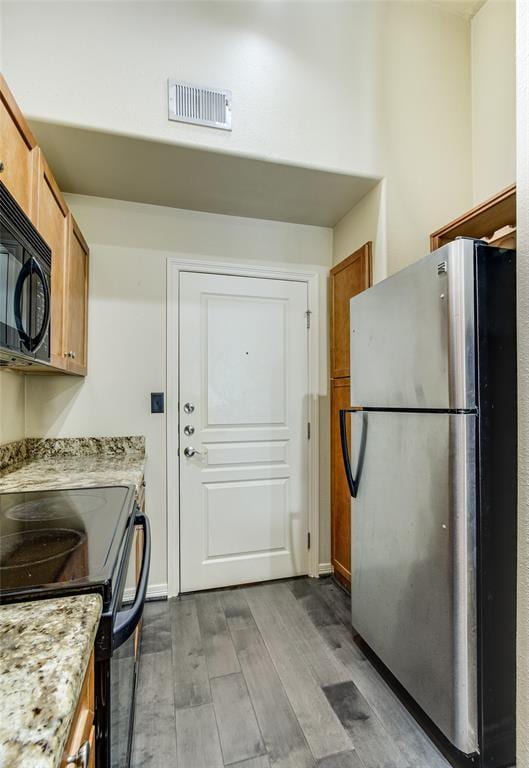 kitchen featuring light stone counters, light wood-type flooring, and black appliances