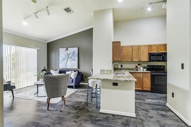 kitchen with a kitchen bar, sink, ornamental molding, kitchen peninsula, and black appliances