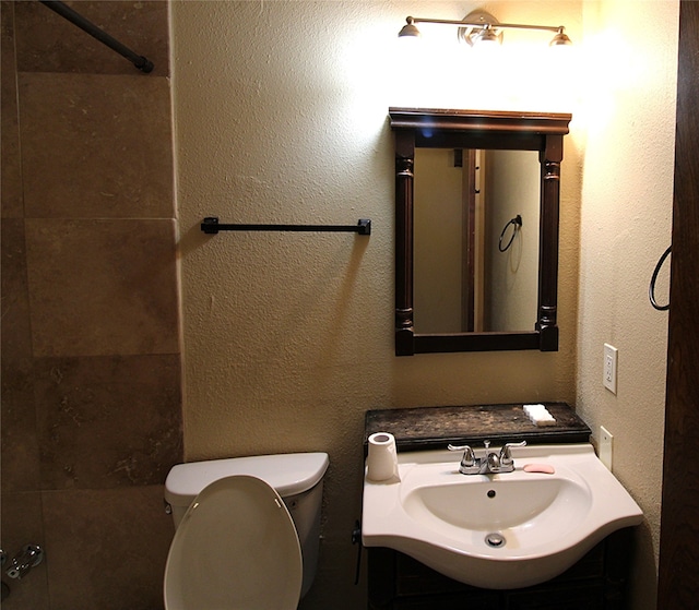 bathroom with toilet, walk in shower, and sink