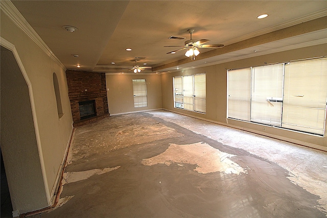 unfurnished living room featuring a brick fireplace, ceiling fan, crown molding, and a tray ceiling