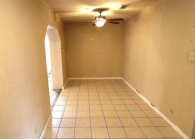 empty room with ceiling fan, light tile patterned floors, and a textured ceiling