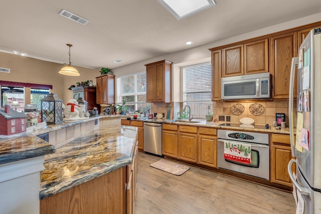 kitchen with stainless steel appliances, sink, pendant lighting, and light stone counters