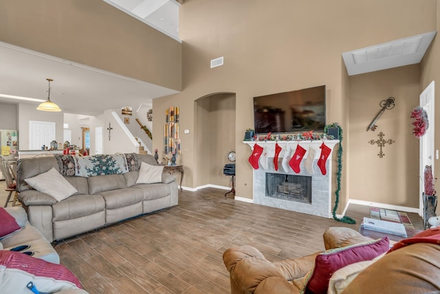 living room featuring a stone fireplace, hardwood / wood-style floors, and a high ceiling