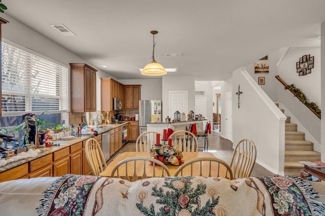 kitchen with pendant lighting, sink, appliances with stainless steel finishes, backsplash, and light stone countertops