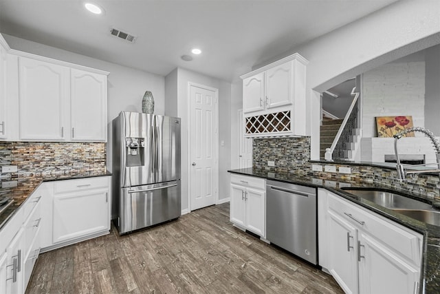 kitchen with white cabinets, decorative backsplash, sink, and stainless steel appliances