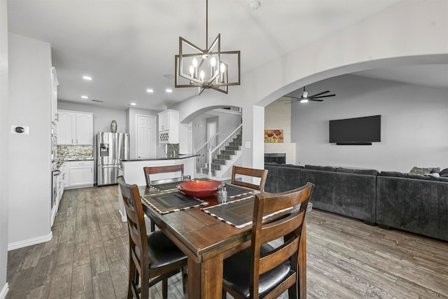 dining space featuring a fireplace, hardwood / wood-style floors, and ceiling fan with notable chandelier