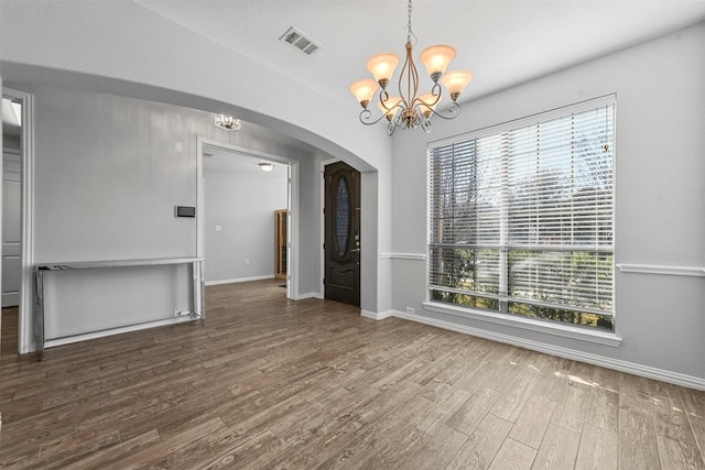 unfurnished dining area featuring a wealth of natural light, hardwood / wood-style floors, and a chandelier