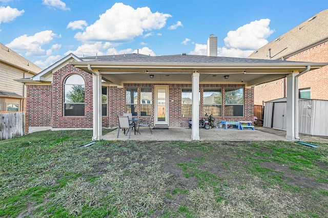 back of house with a patio area, a storage shed, and a yard