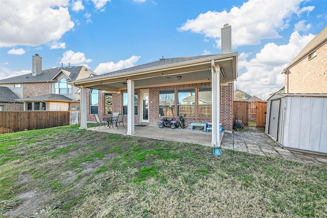 rear view of property featuring a lawn, a patio area, and a shed